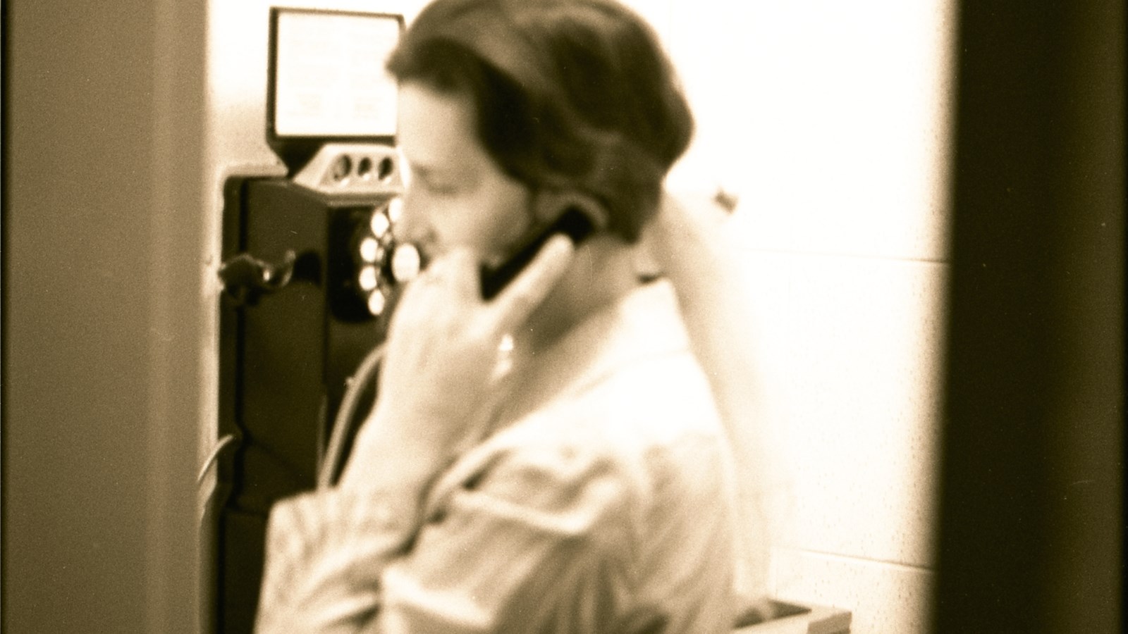 Femme utilisant un téléphone public. [197-?].
